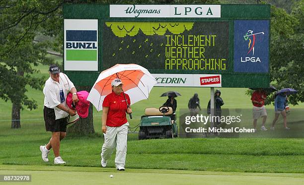 Jiyai Shin of South Korea arrives at the 18th green in heavy rain during the final round of the Wegmans LPGA at Locust Hill Country Club held on June...