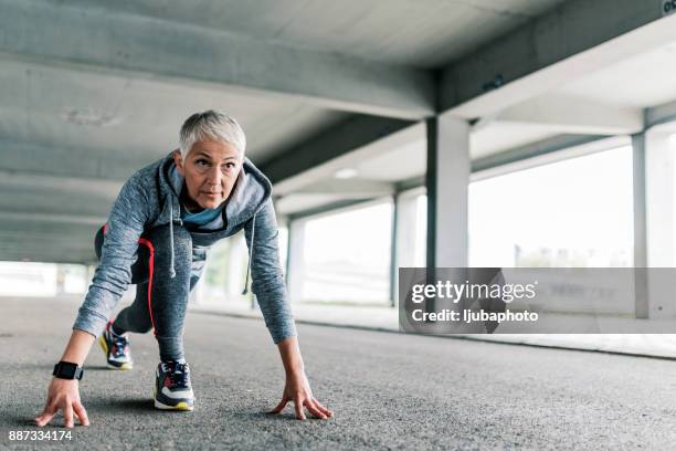 senior female in the starting position to run - first gray hair stock pictures, royalty-free photos & images