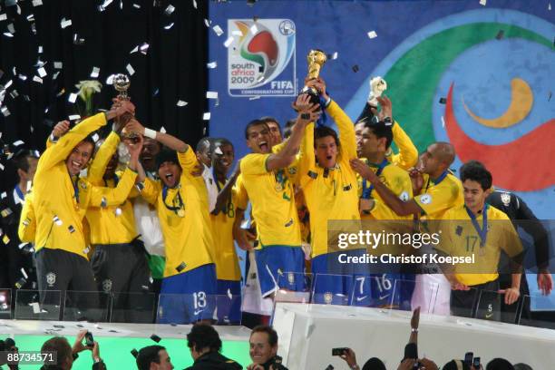 Elano of Brazil lifts the trophy as his team mates celebrate following their victory at the end of the FIFA Confederations Cup Final between USA and...