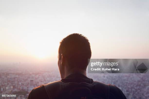 caucasian man looking down the cityscape of tokyo - tegenlicht stockfoto's en -beelden