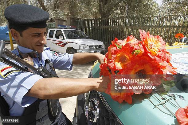 An Iraqi police officer tapes down plastic flowers to the front of a police vehicles as the nation prepares for the official withdrawal of US troops...