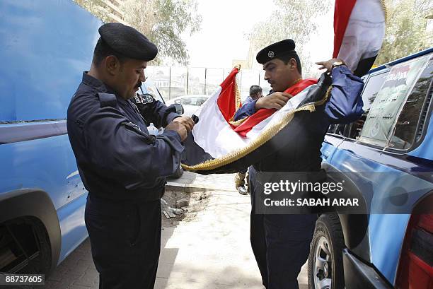 Iraqi police officers secure their national flag as they decorate their vehices in preparation for the official withdrawal of US troops from cities...