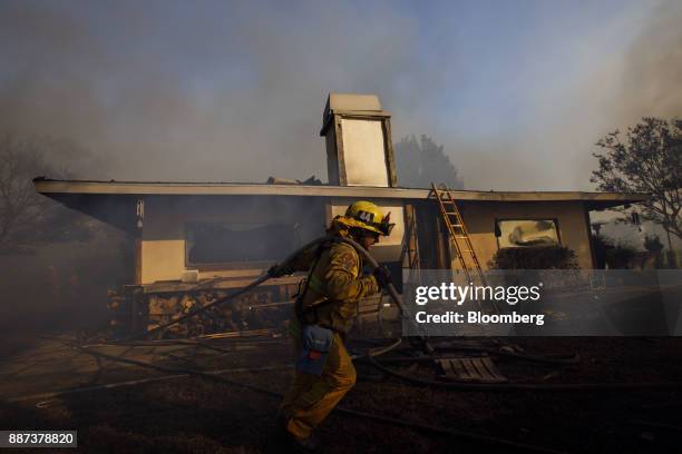 Firefighter pulls a hose line while working to save homes during the Skirball Fire in the Bel Air neighborhood of Los Angeles, California, U.S., on...