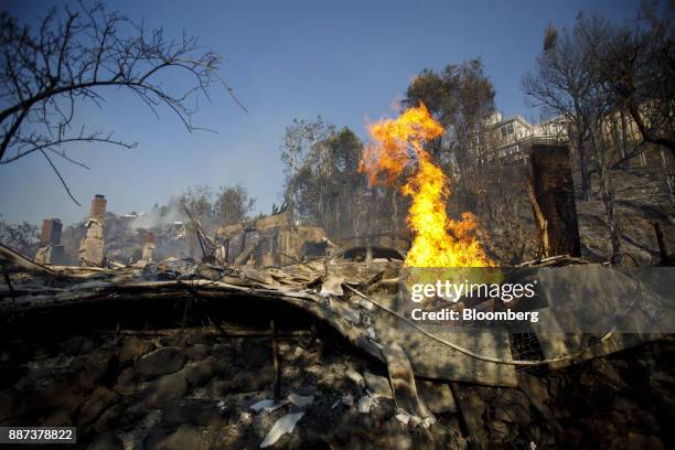 Flames burn from a destroyed home's natural gas line during the Skirball Fire in the Bel Air neighborhood of Los Angeles, California, U.S., on...