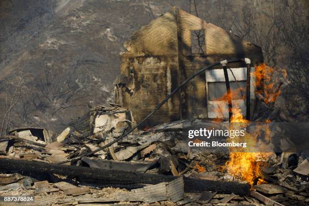 Flames burn from a destroyed home's natural gas line during the Skirball Fire in the Bel Air neighborhood of Los Angeles, California, U.S., on...