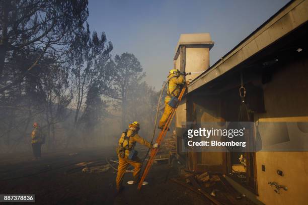 Firefighters hose down the roof of a partially burned home during the Skirball Fire in the Bel Air neighborhood of Los Angeles, California, U.S., on...