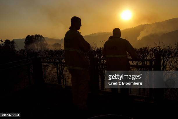 The silhouettes of firefighters are seen as they keep watch over a home while the sun sets during the Skirball Fire in the Bel Air neighborhood of...
