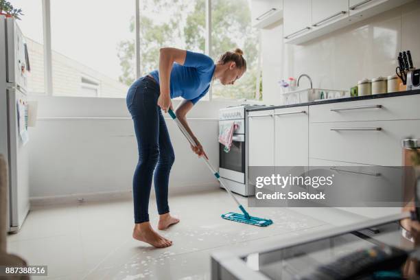 jonge vrouwelijke vloer schoonmaken - huishoudelijk werk stockfoto's en -beelden