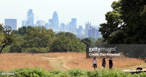 People walk past a view of the City of London in Richmond Park on June 29, 2009 in London, England. The Met Office has announced a weather warning...
