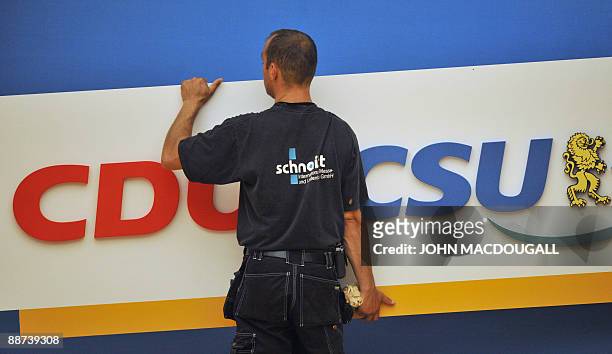 Worker removes a CDU and CSU logo after a special congress of the Christian Democratic Union and the Christian Social Union to put forth their agenda...