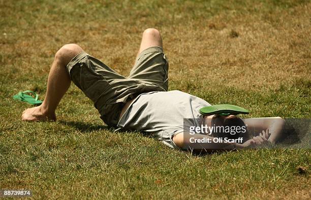 Man shades his face with one of his flip-flops as he relaxes in the sun in Hyde Park on June 29, 2009 in London, England. The Met Office has...