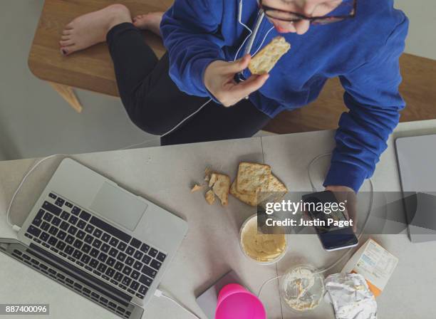 teenager having a quick snack whilst on smartphone - cracker snack 個照片及圖片檔