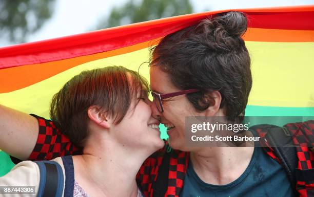 Alice Bennett and her partner Miranda Hill kiss as they gather with a crowd of people to watch a large television screen at Federation Square as it...