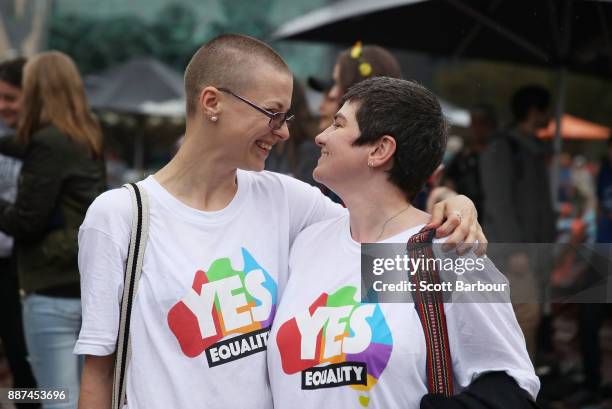 Tracy Clark and her partner Justyna Greinart embrace as they gather with a crowd of people to watch a large television screen at Federation Square as...