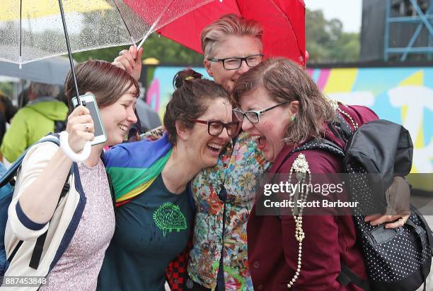 Group of women react as they gather with a crowd of people to watch a large television screen at Federation Square as it is announced that same-sex...