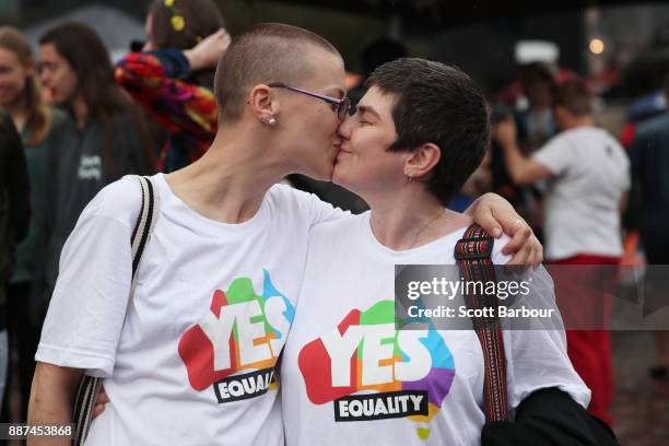 Tracy Clark and her partner Justyna Greinart embrace as they gather with a crowd of people to watch a large television screen at Federation Square as...