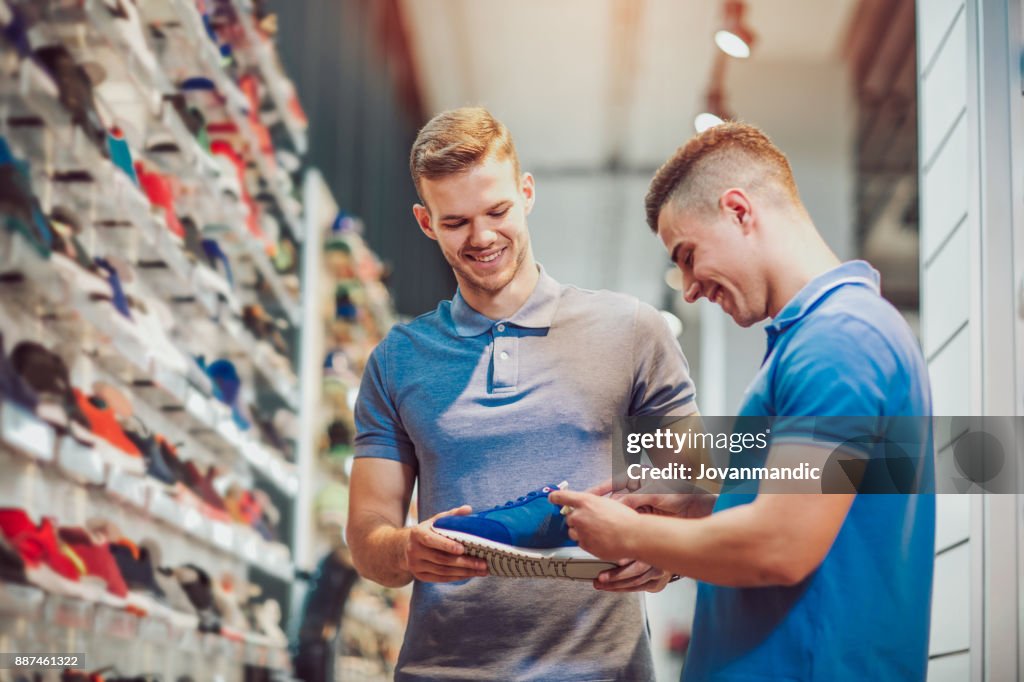 Two man deciding on new sports shoes in sports store