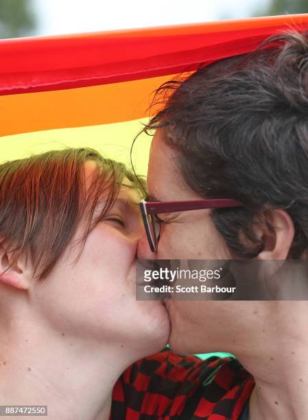 Alice Bennett and her partner Miranda Hill kiss as they gather with a crowd of people to watch a large television screen at Federation Square as it...