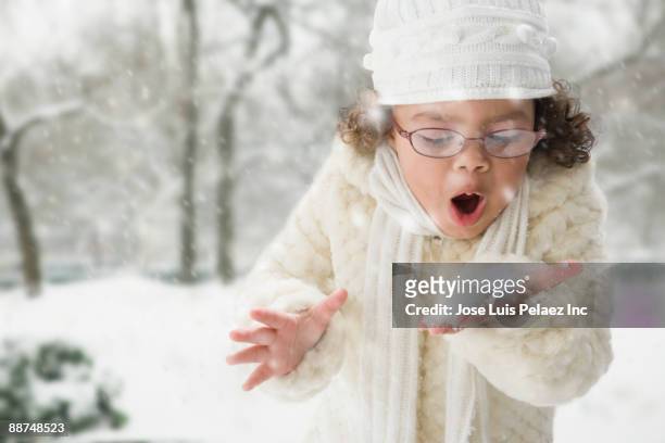 hispanic girl enjoying snow outdoors - schnee pusten stock-fotos und bilder