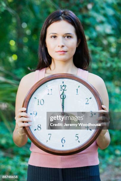 hispanic woman  holding clock in forest - clocks go forward - fotografias e filmes do acervo