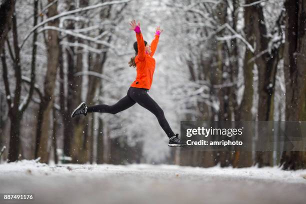 jump! - side view woman jumping for joy in winter - winter jumper stock pictures, royalty-free photos & images