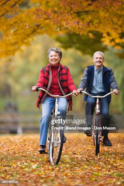 african couple riding bicycles in park in autumn - fall in seattle stock pictures, royalty-free photos & images