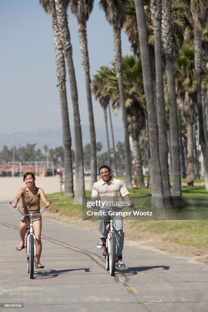 Young couple riding bicycles at beach