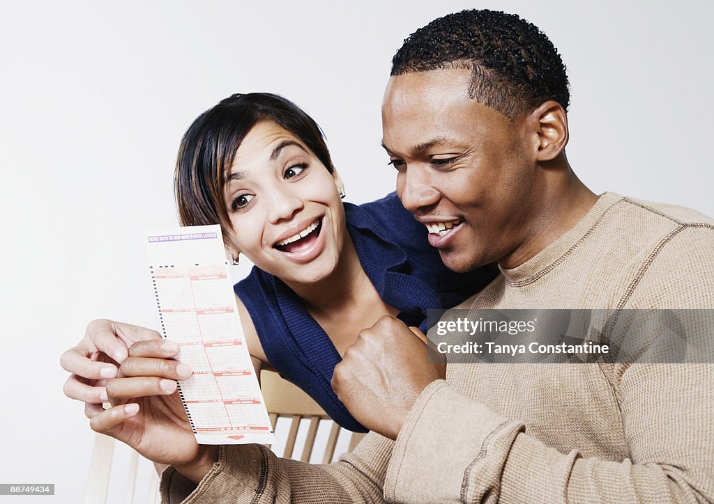 Excited couple looking at lottery ticket