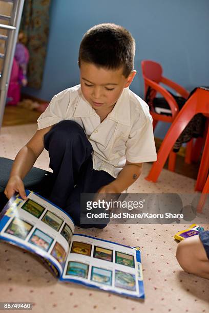 asian boy reading magazine in bedroom - trading card stockfoto's en -beelden