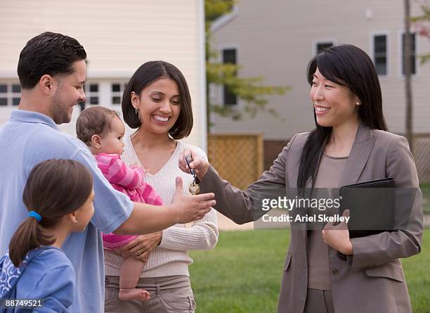 hispanic family receiving keys to house from real estate agent - agent and handing keys stock-fotos und bilder