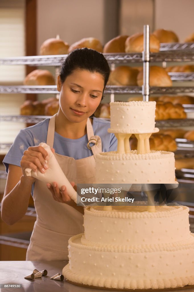 Hispanic woman decorating wedding cake