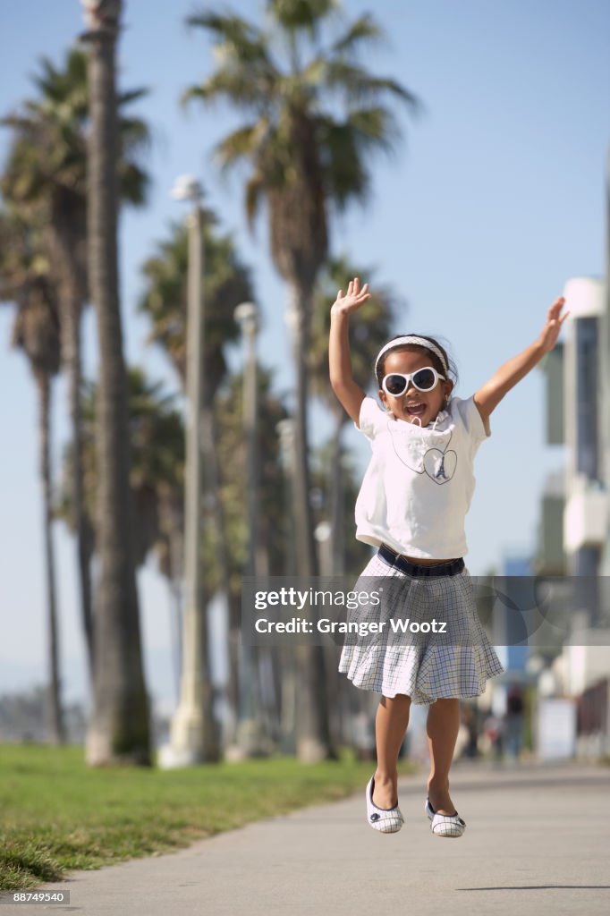 Young mixed race girl wearing sunglasses and jumping