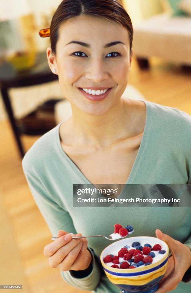 Asian woman eating yogurt with berries