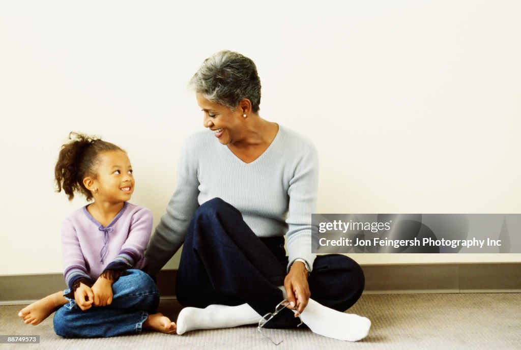 African grandmother and granddaughter sitting on floor