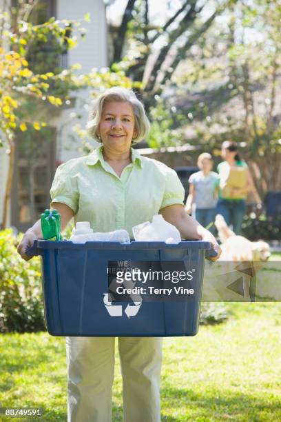 hispanic woman carrying recycling bin - altglasbehälter stock-fotos und bilder