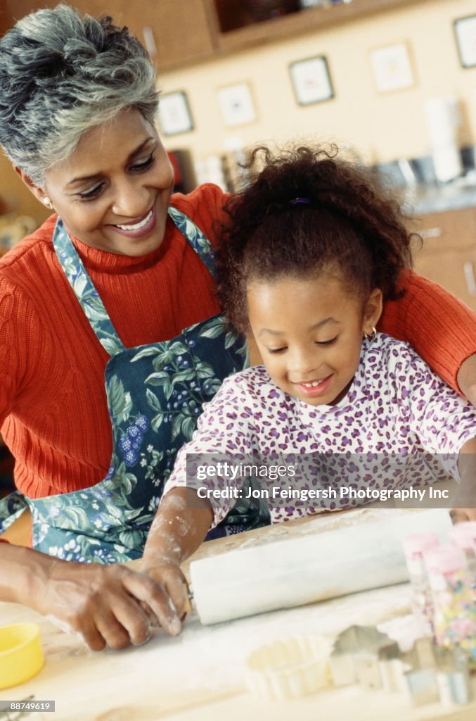 African grandmother and granddaughter rolling dough