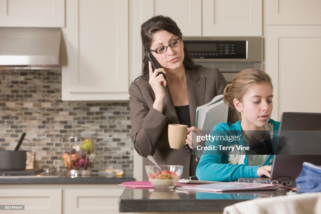 Hispanic mother watching daughter using laptop