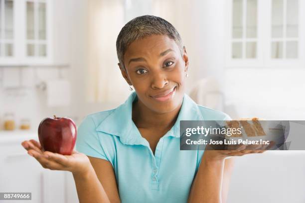 african woman choosing snack - holding two things foto e immagini stock