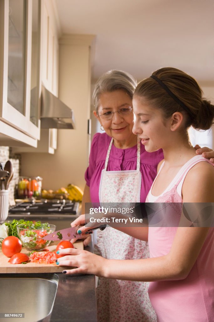 Hispanic grandmother and granddaughter cutting vegetables