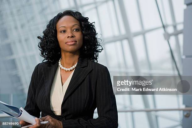 african businesswoman holding paperwork - woman in black suit stock pictures, royalty-free photos & images