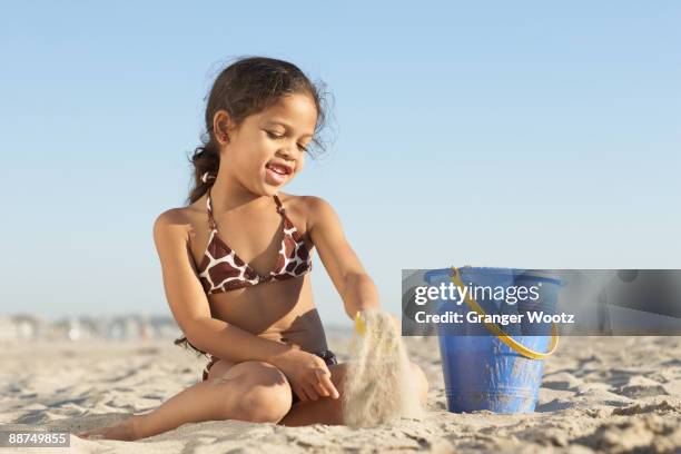 young mixed race girl playing at beach - digging beach photos et images de collection