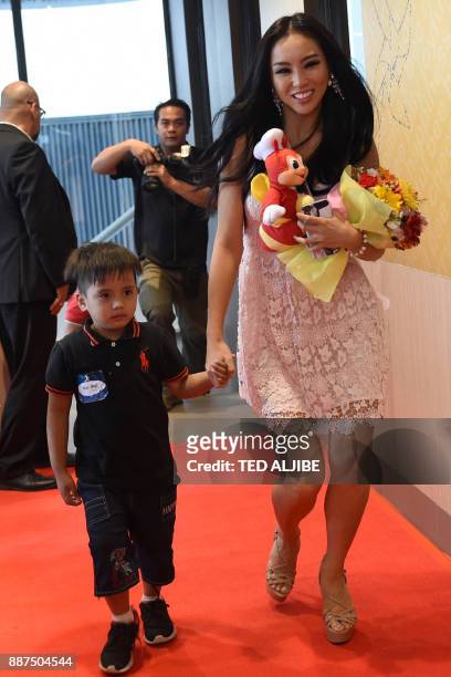 Miss Universe contestant Cho Se Whee Of South Korea walks with a child from an orphanage during a visit to a popular fast food restaurant in Manila...