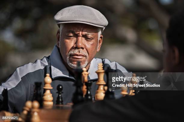 senior african man playing chess outdoors - playing chess stock-fotos und bilder