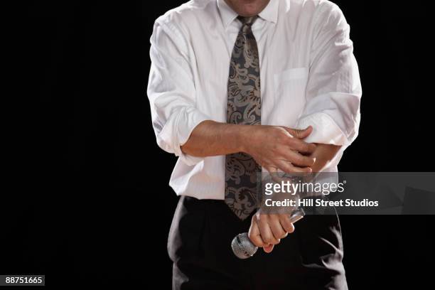 hispanic man holding microphone and rolling up shirtsleeve - roll shirt stock pictures, royalty-free photos & images