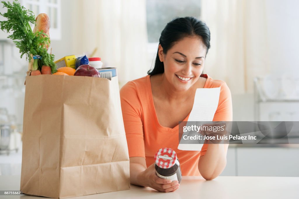 Hispanic woman looking at grocery receipt