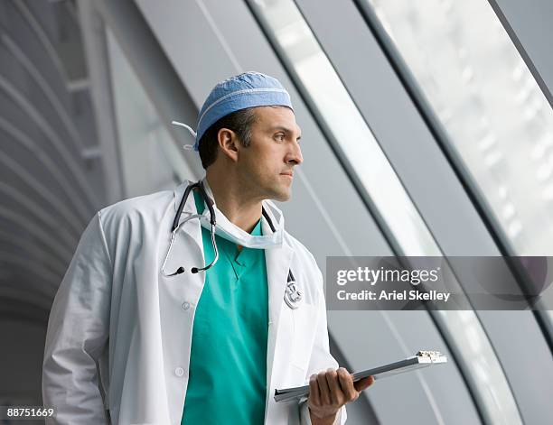 hispanic doctor holding medical chart in hospital - arzt profil stock-fotos und bilder