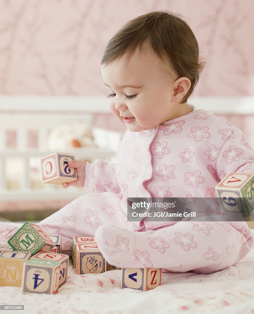 Mixed race baby girl playing with alphabet blocks