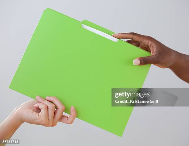 african woman handing co-worker a folder - delegating stock-fotos und bilder