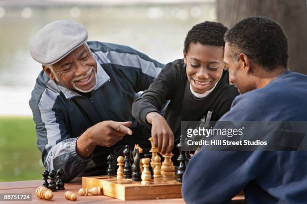 african boy playing chess against father outdoors - playing chess stock-fotos und bilder