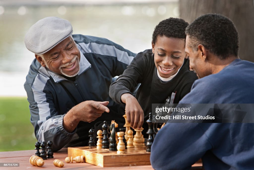 African boy playing chess against father outdoors